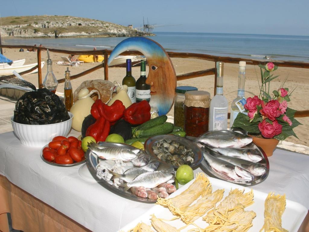 a table with fish and vegetables and bottles of wine at Althea Village Residence in Vieste