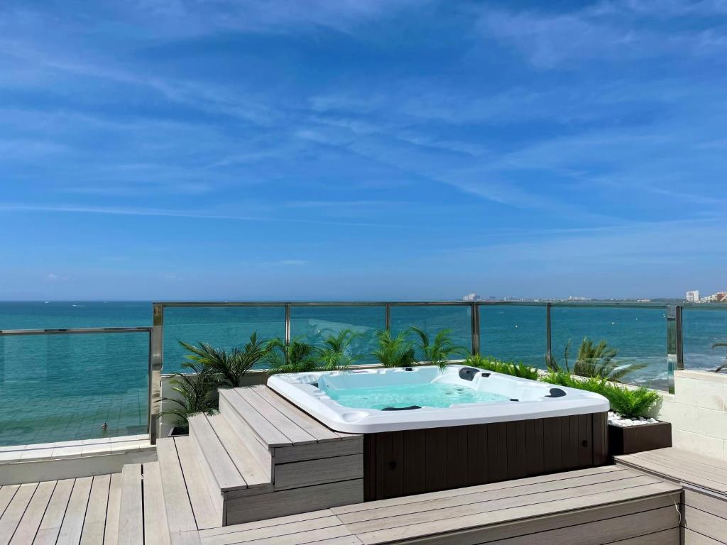 uma banheira de hidromassagem num deque com vista para o oceano em Apartamentos Stella Maris em Roses