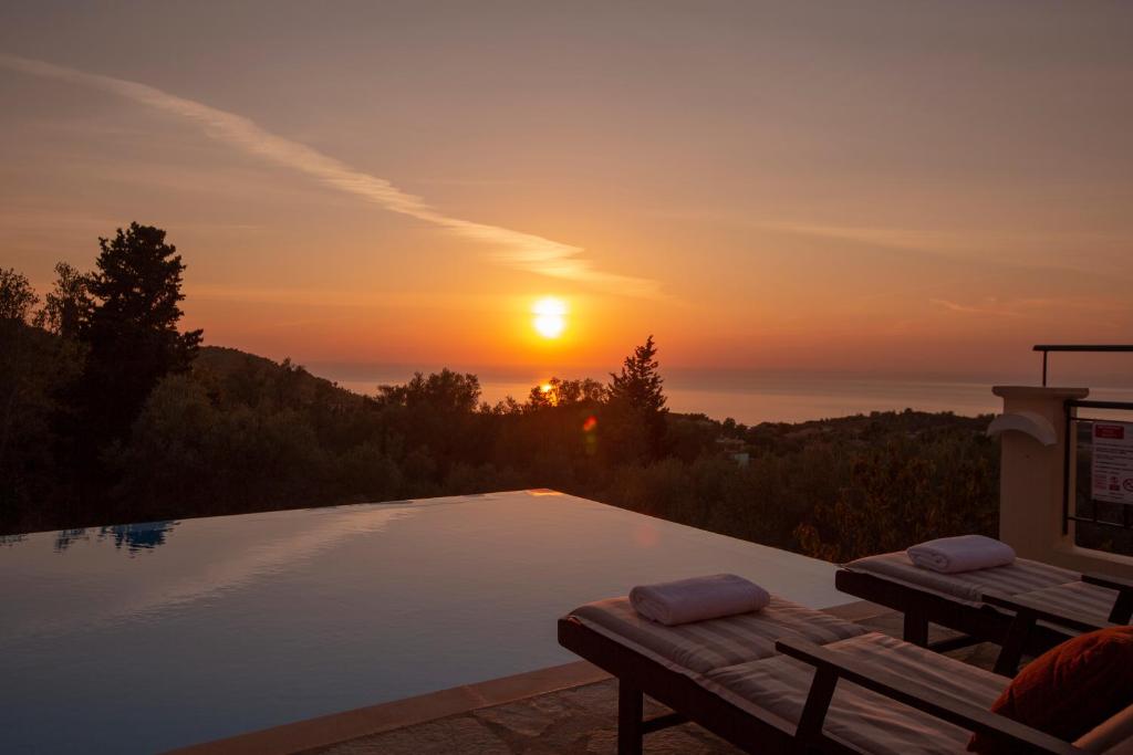 una piscina con un tramonto sullo sfondo di Villa Belvedere Rosa a Tsoukalades