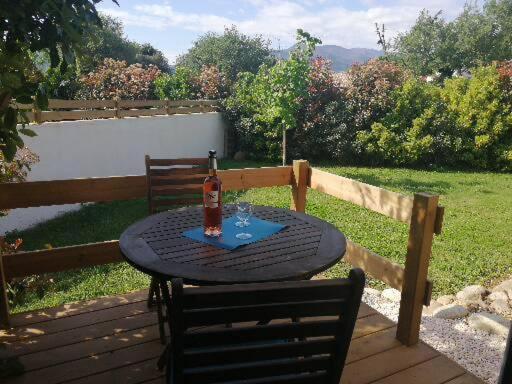 a table with a bottle of wine sitting on a deck at Appartement de vacances à la campagne in Saint-Jean-Pla-de-Corts