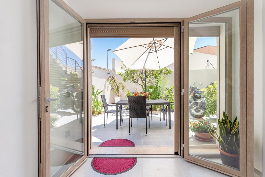 卡布拉斯的住宿－CASA L'ANGOLO FIORITO，滑动玻璃门通向带桌子和遮阳伞的天井