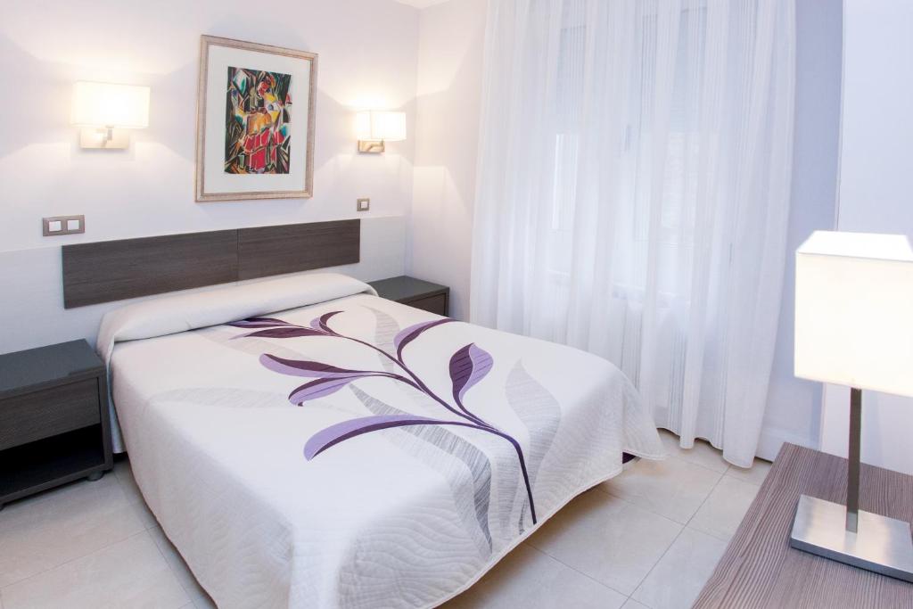 a bed room with a white bedspread and pillows at Pensión Plaza in Santander