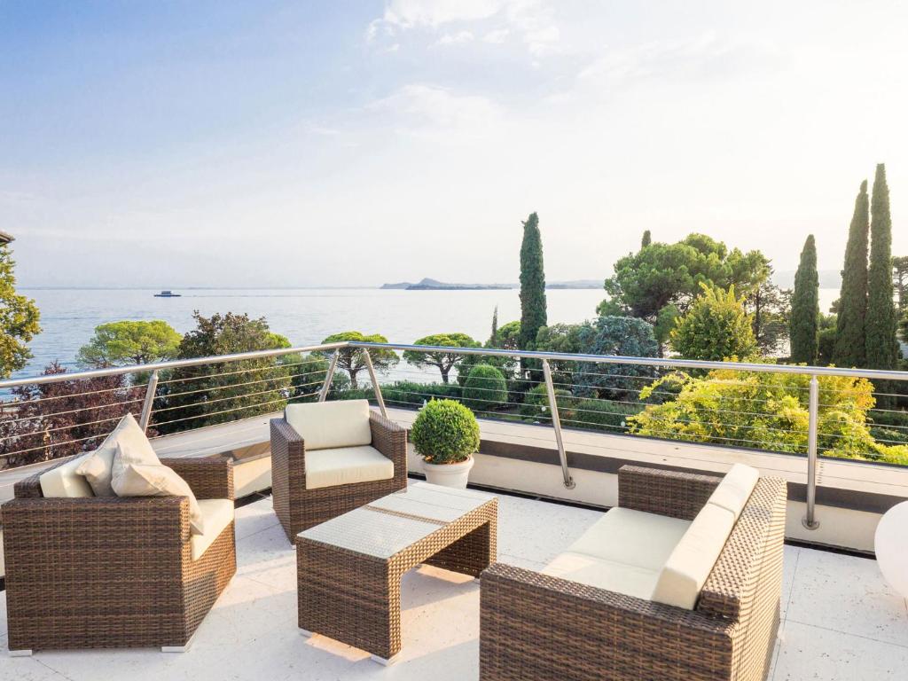 een balkon met rieten meubels en uitzicht op de oceaan bij Corte Fasanella 31 - Gardagate in Toscolano Maderno