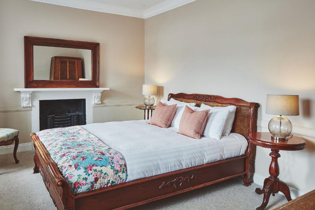 a bedroom with a bed with a fireplace and a mirror at Brambles of Inveraray in Inveraray