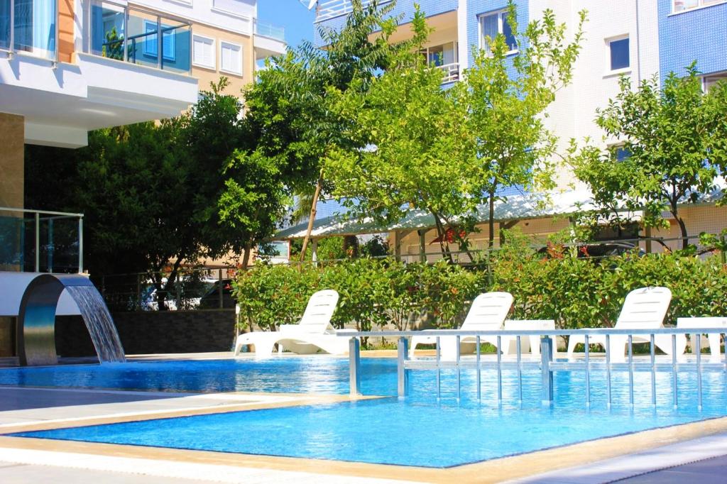 a swimming pool with white chairs and a fountain at Alfa Apart Hotel in Antalya