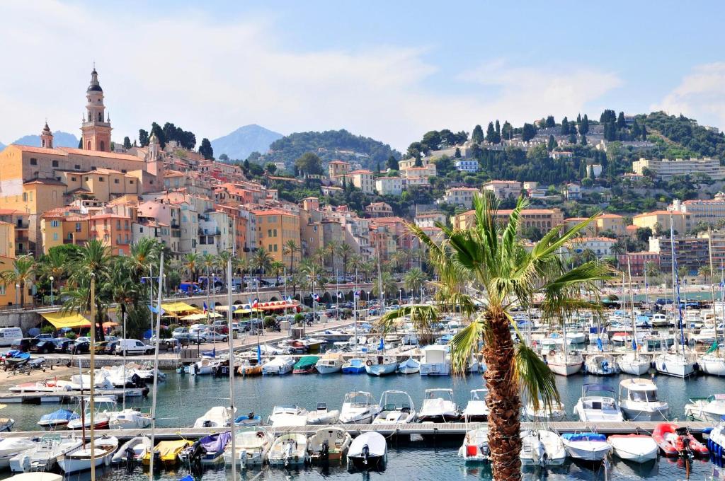 a harbor in a city with boats in the water at Hôtel Miléade L'Orangeraie - Menton in Menton