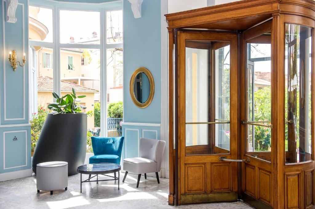 a room with a wooden door and chairs at Hôtel Miléade L'Orangeraie - Menton in Menton