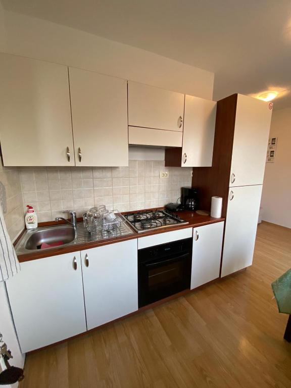 kuchnia z białymi szafkami, zlewem i kuchenką w obiekcie Varga apartment w mieście Opatija