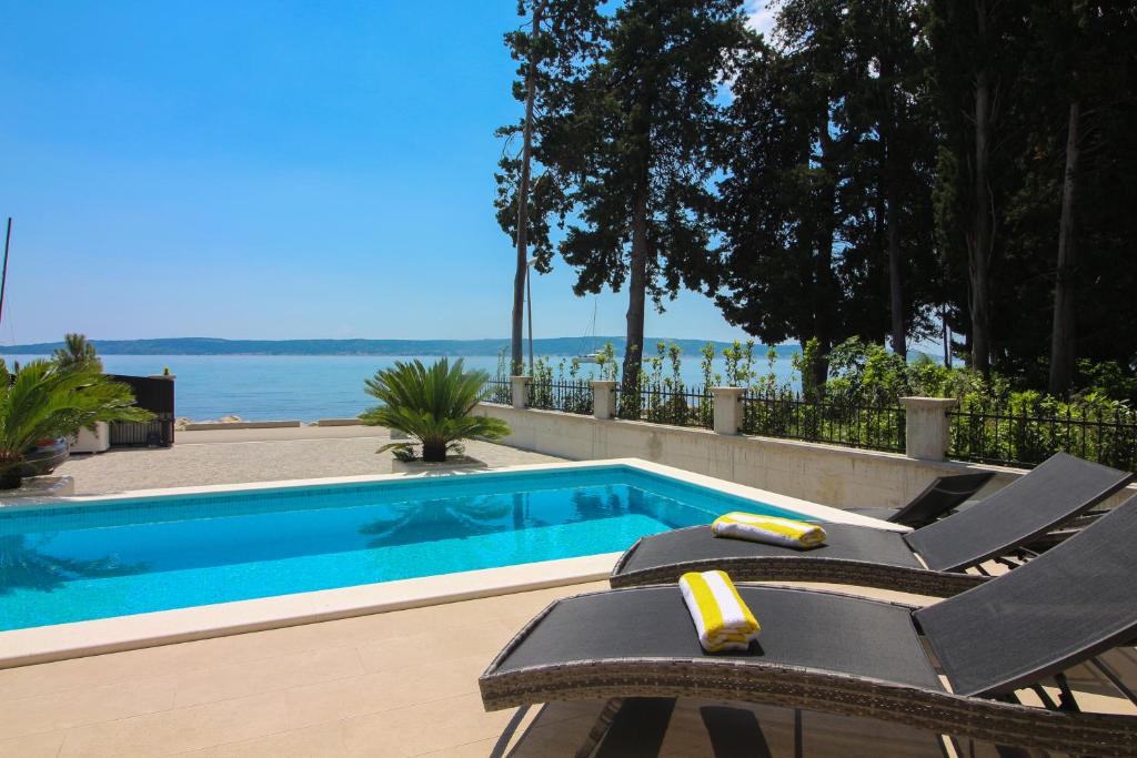 ein Pool mit zwei Liegestühlen daneben in der Unterkunft Villa Beachfront Sea Palace in Kaštela