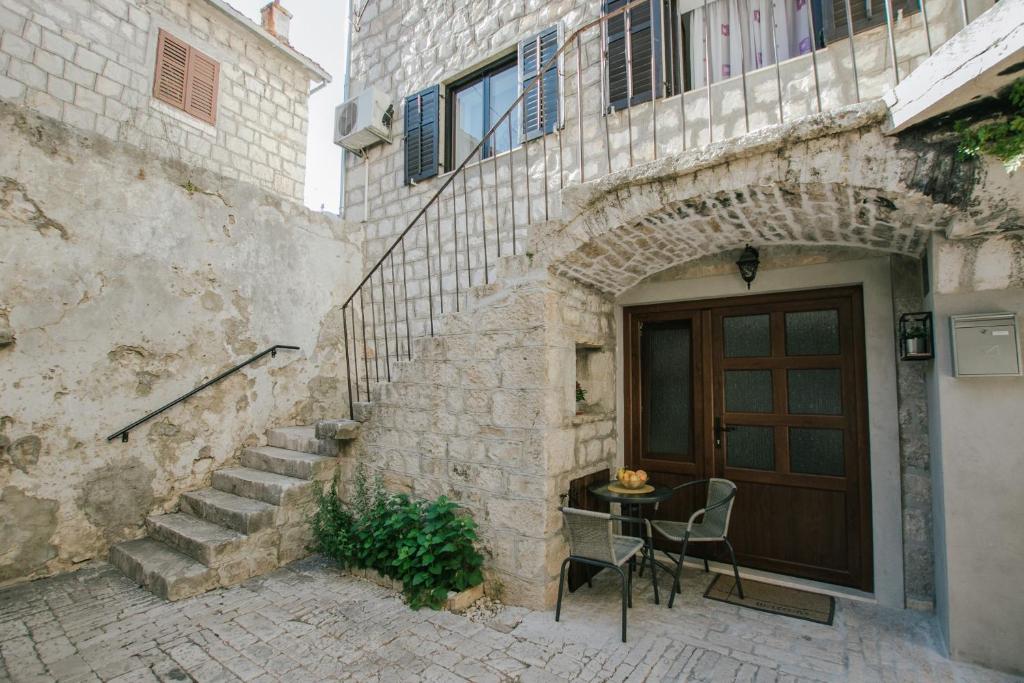 ein Steingebäude mit einer Tür, einem Tisch und Stühlen in der Unterkunft Modern traditional apartment w patio near beach in Kaštela