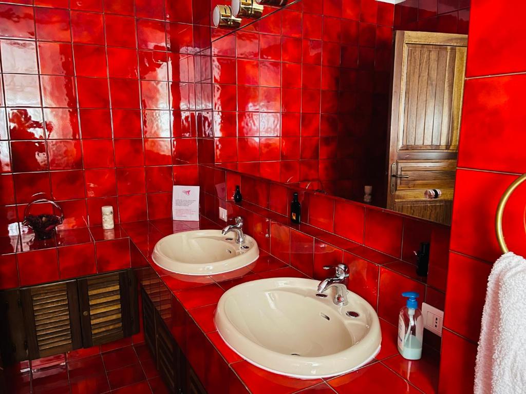 La salle de bains est pourvue de carrelage rouge et de deux lavabos. dans l'établissement CASA DEL CORSO, à Cinisi