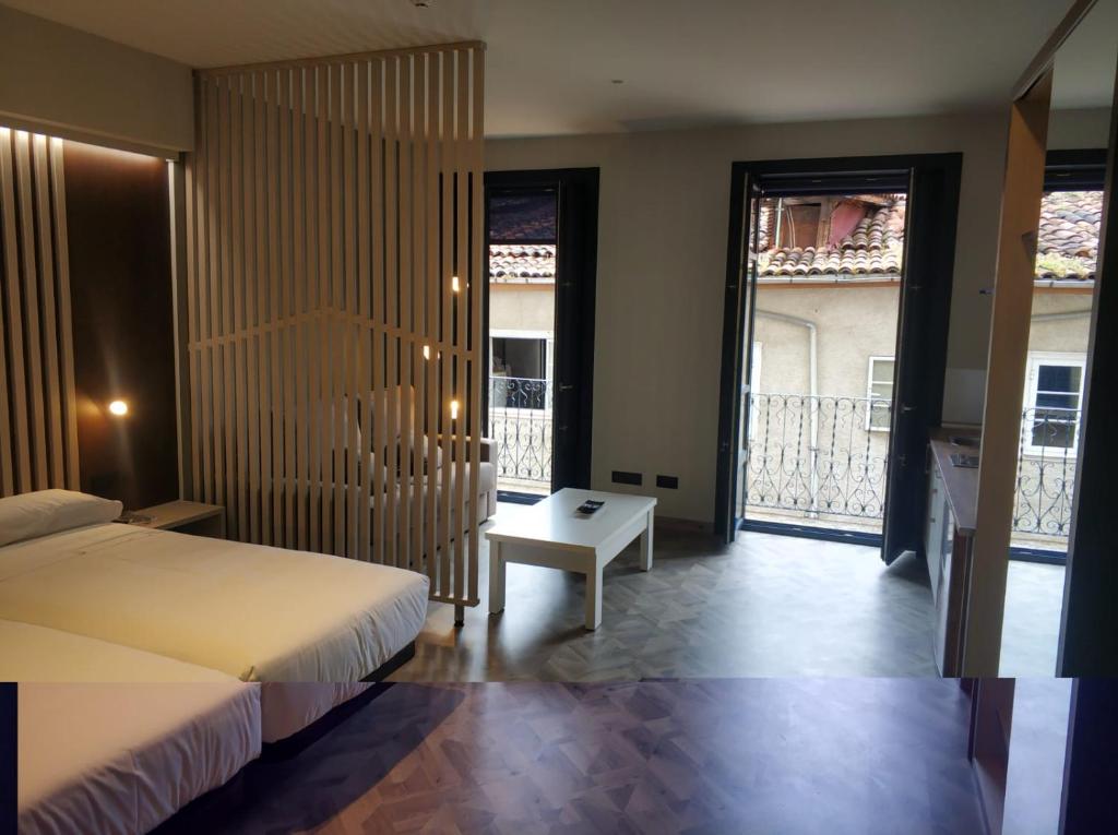 sypialnia z łóżkiem, stołem i oknami w obiekcie Apartamentos Turísticos y Habitaciones Cidade Vella w mieście Ourense