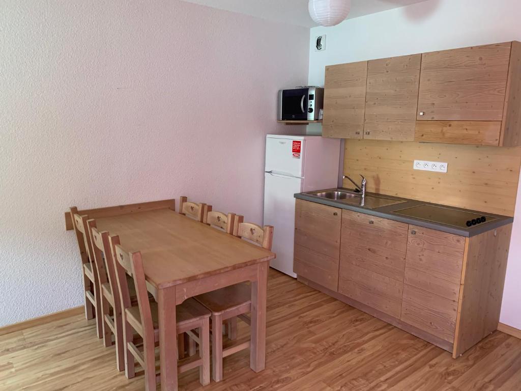 a kitchen with a table and a sink and a refrigerator at APPARTEMENT À LA MONTAGNE à LA MEIJE BLANCHE in Villar-dʼArène