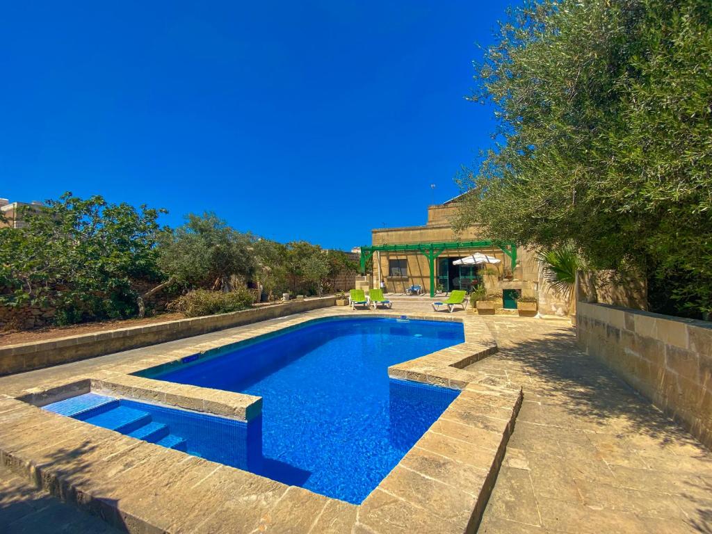 una piscina con un banco junto a una casa en Villa Xini, en Xewkija