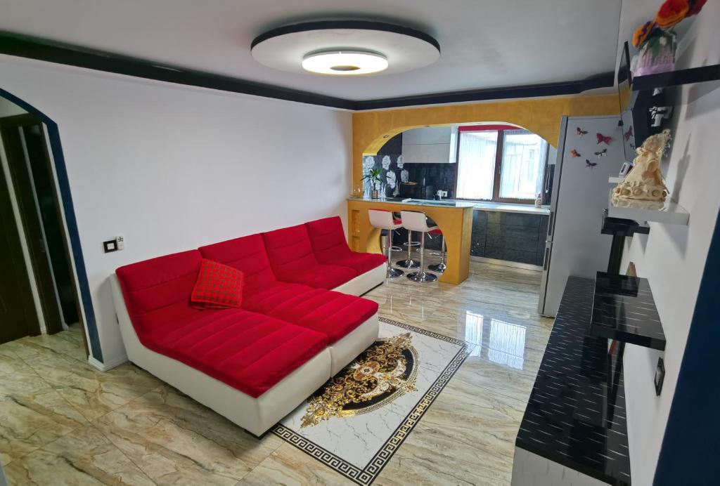 a living room with a red couch and a kitchen at Apartament Mara in Jurilovca