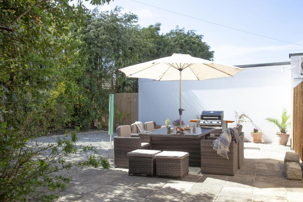 a patio with a table and an umbrella and chairs at Bridge Apartment in Perranporth