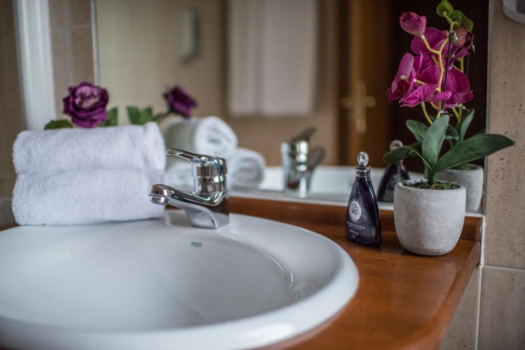 ein Badezimmer mit einem Waschbecken, einem Spiegel und Blumen in der Unterkunft Villa de Elciego in Elciego