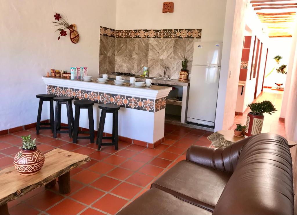a kitchen with a bar with stools and a couch at Villa del Sol - Apartamentos Turísticos in Sáchica