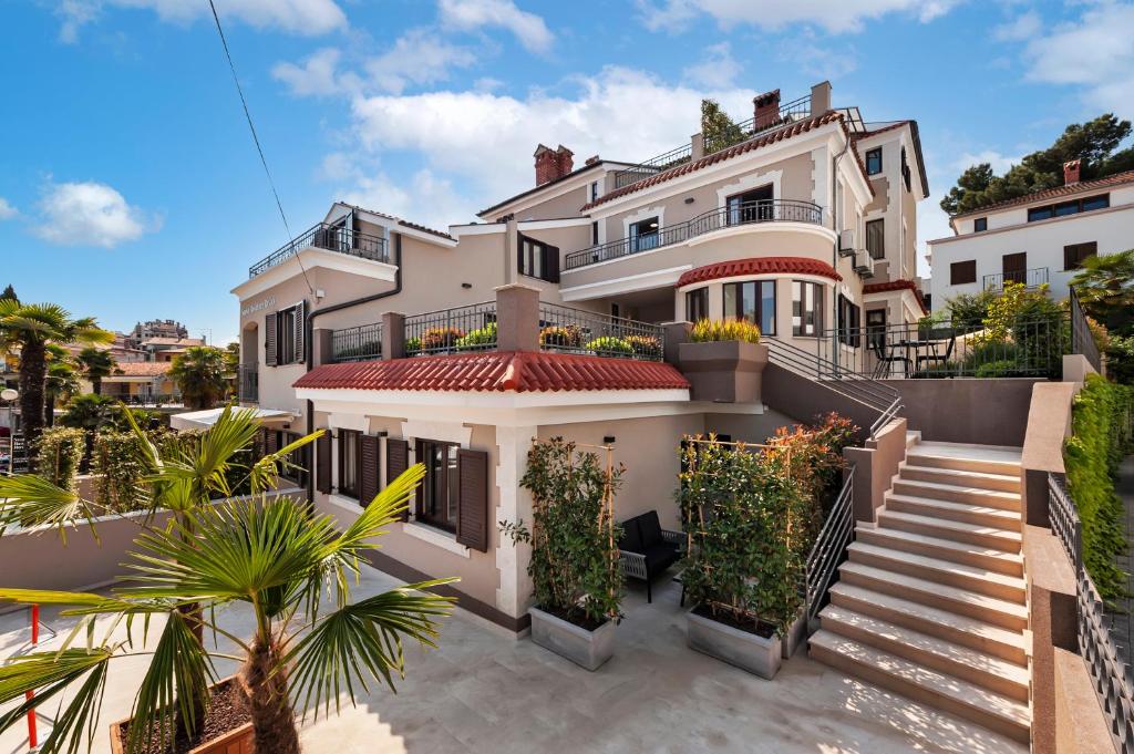 a large white house with stairs and plants at Sunset Residence Rovinj in Rovinj