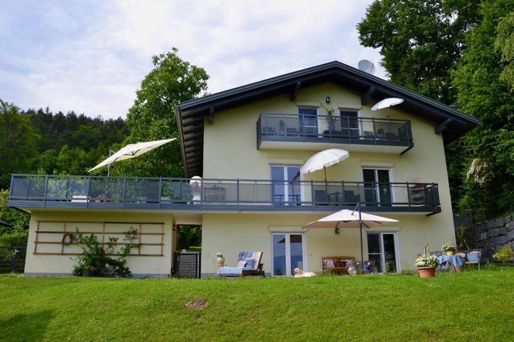 a house with a balcony and a lawn at Schwalbennest Velden in Velden am Wörthersee