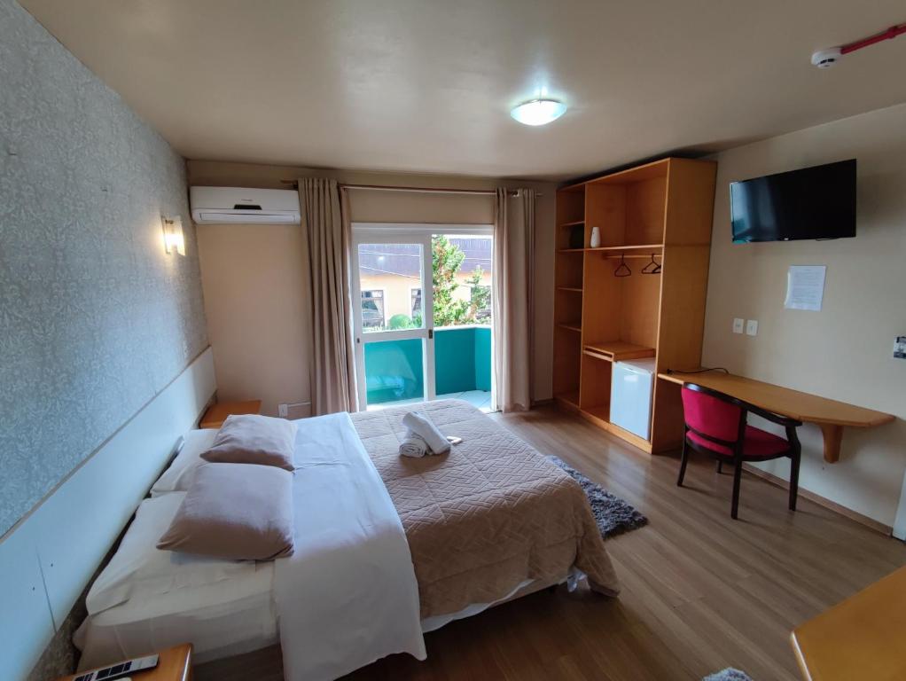 1 dormitorio con cama, escritorio y ventana en Pousada Ruppenthal, en Canela