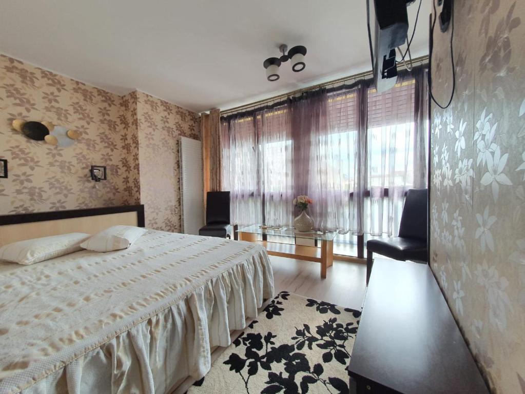 a bedroom with a bed and a table and windows at Vila CLASS in Vatra Dornei