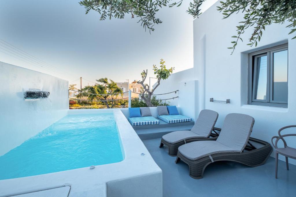 a swimming pool in a house with two chairs at Majestic Sky Luxury Suites in Megalochori