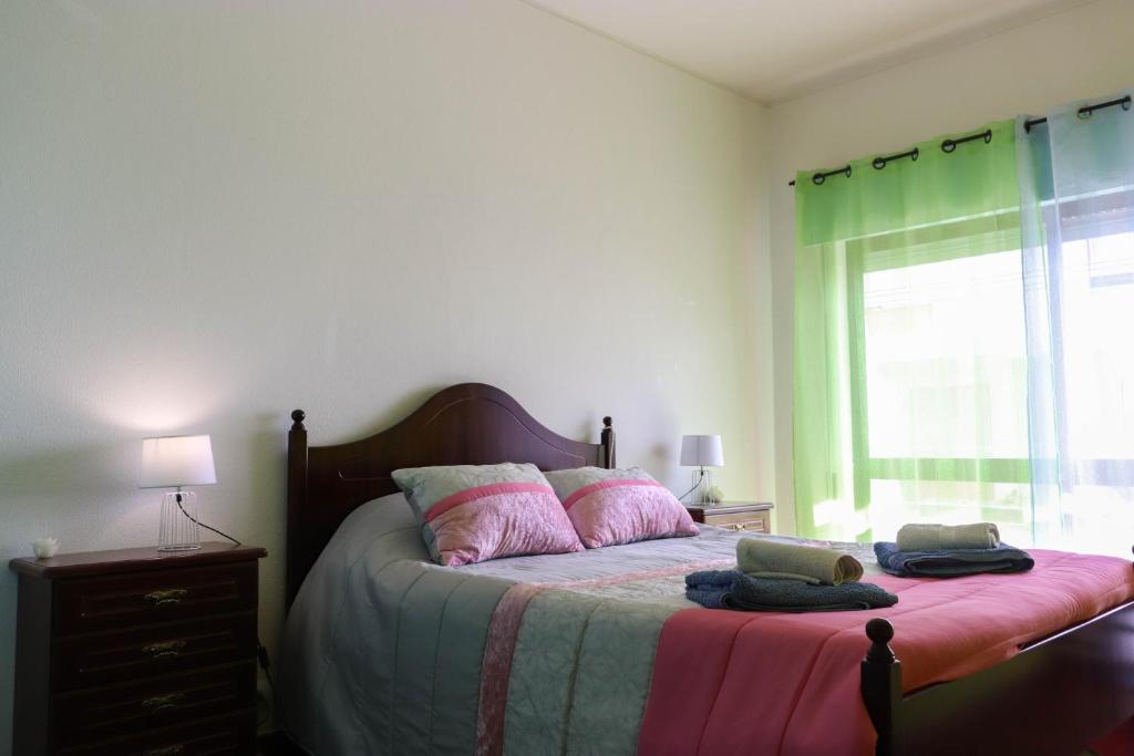 - une chambre dotée d'un lit avec des rideaux roses et verts dans l'établissement Apartamento com vista mar, à Nazaré