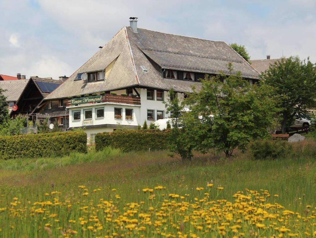 ein großes weißes Haus auf einem Blumenfeld in der Unterkunft Pension Wiesengrund in Schluchsee