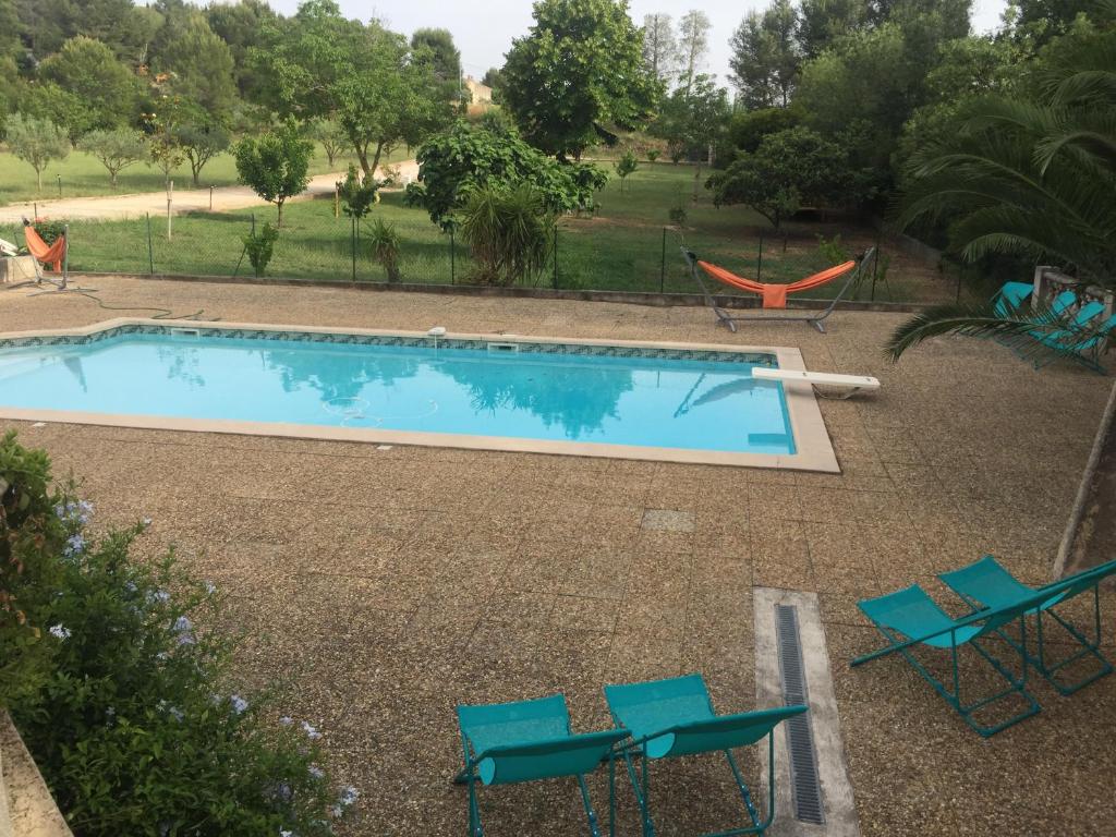 a swimming pool with chairs and a hammock at Sur les pas de Pagnol in Aubagne