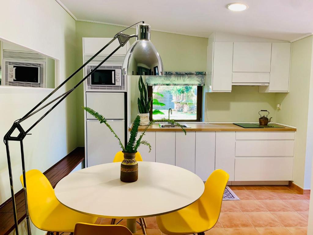 een keuken met een witte tafel en gele stoelen bij Pedreiras Cottage Rias Baixas in Pontevedra