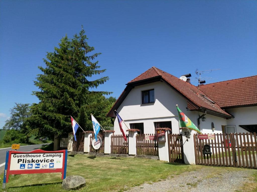ein Haus mit einem Zaun mit Flaggen davor in der Unterkunft Camping & Guest House Pliskovice in Mirovice