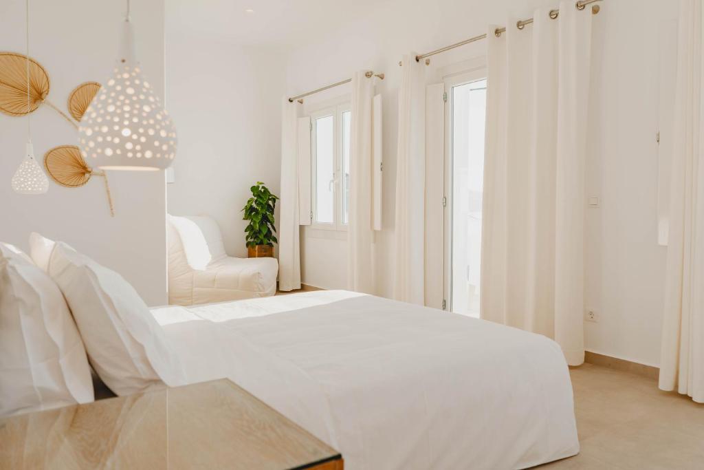 a white bedroom with a white bed and a chair at BAY VIEW RESIDENCE in Mikonos