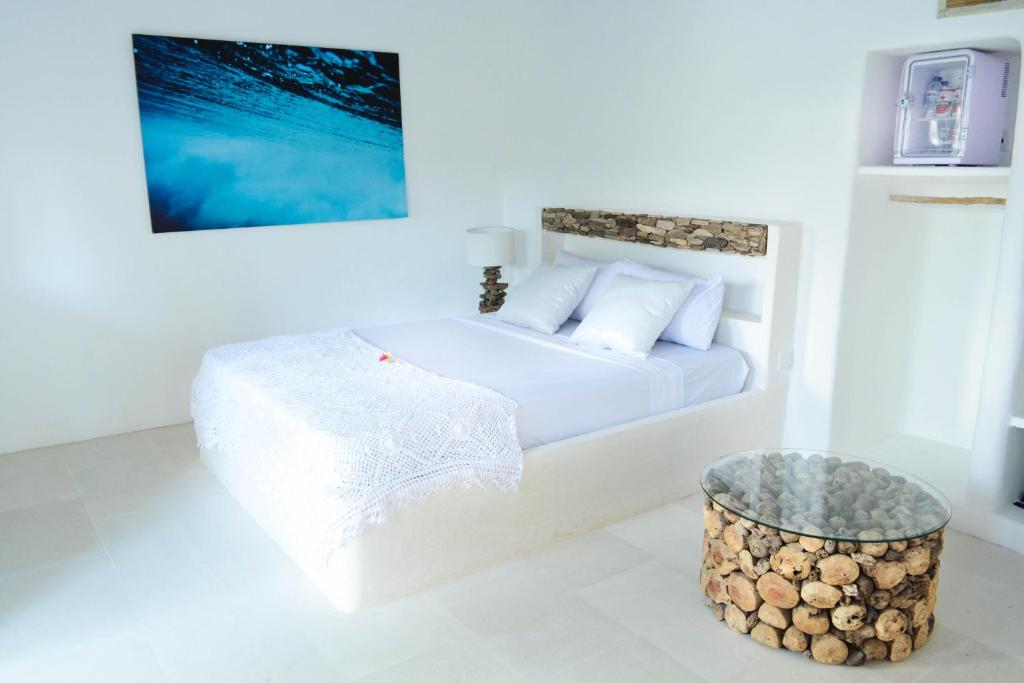 a white bedroom with a bed and a table at Sal Secret Spot in Uluwatu