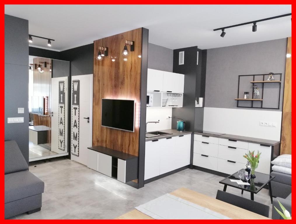 a kitchen with white cabinets and a tv on a wall at Noce w Jelonce - Nowoczesny Apartament typu Studio w Centrum Jeleniej G - z garażem dla 1-4 osób in Jelenia Góra
