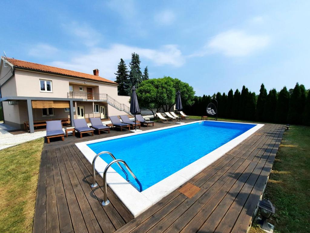 a swimming pool with a wooden deck next to a house at Holiday house in Central Istria with private pool in Žminj