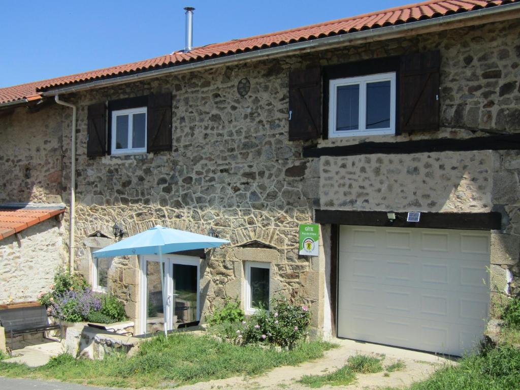 a stone house with a garage and a blue umbrella at GITE DU MORS-DORE in Le Sapt