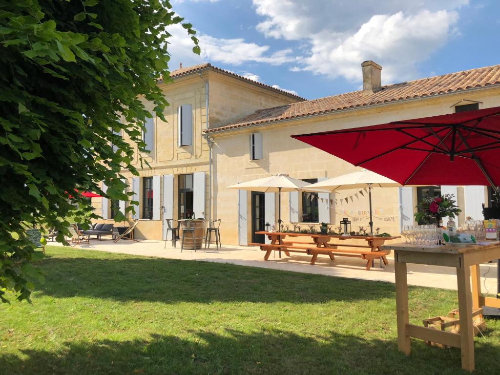 einen roten Regenschirm vor einem Haus in der Unterkunft Chambres d'hôte & Gîte Château Le Conte - Saint Emilion in Saint-Hippolyte