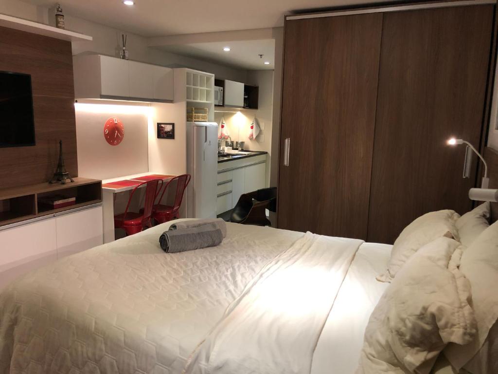 1 Schlafzimmer mit einem großen weißen Bett und einer Küche in der Unterkunft Flat Granja Brasil Itaipava in Petrópolis