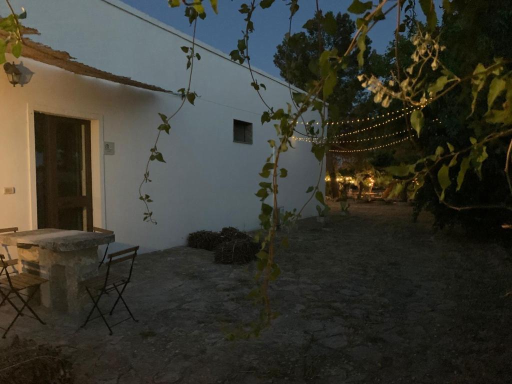 a white building with a table and chairs in a yard at masseria chianca " Le Gravine" in Mottola