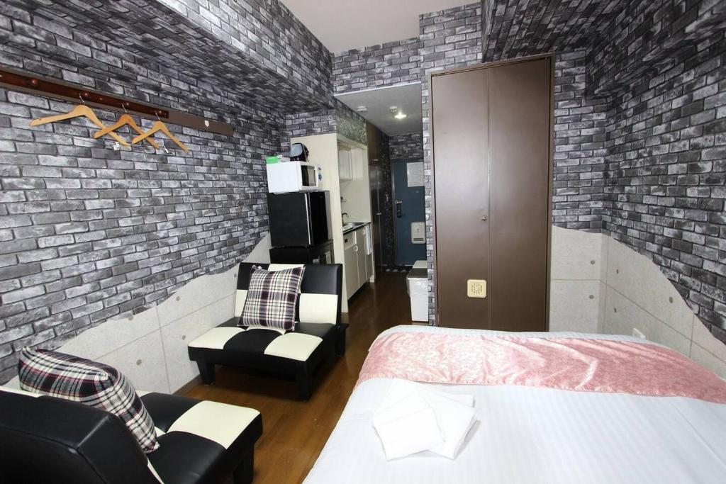 a bedroom with a brick wall and a bed and chairs at La Foret Fujimi - Vacation STAY 45794v in Hiroshima