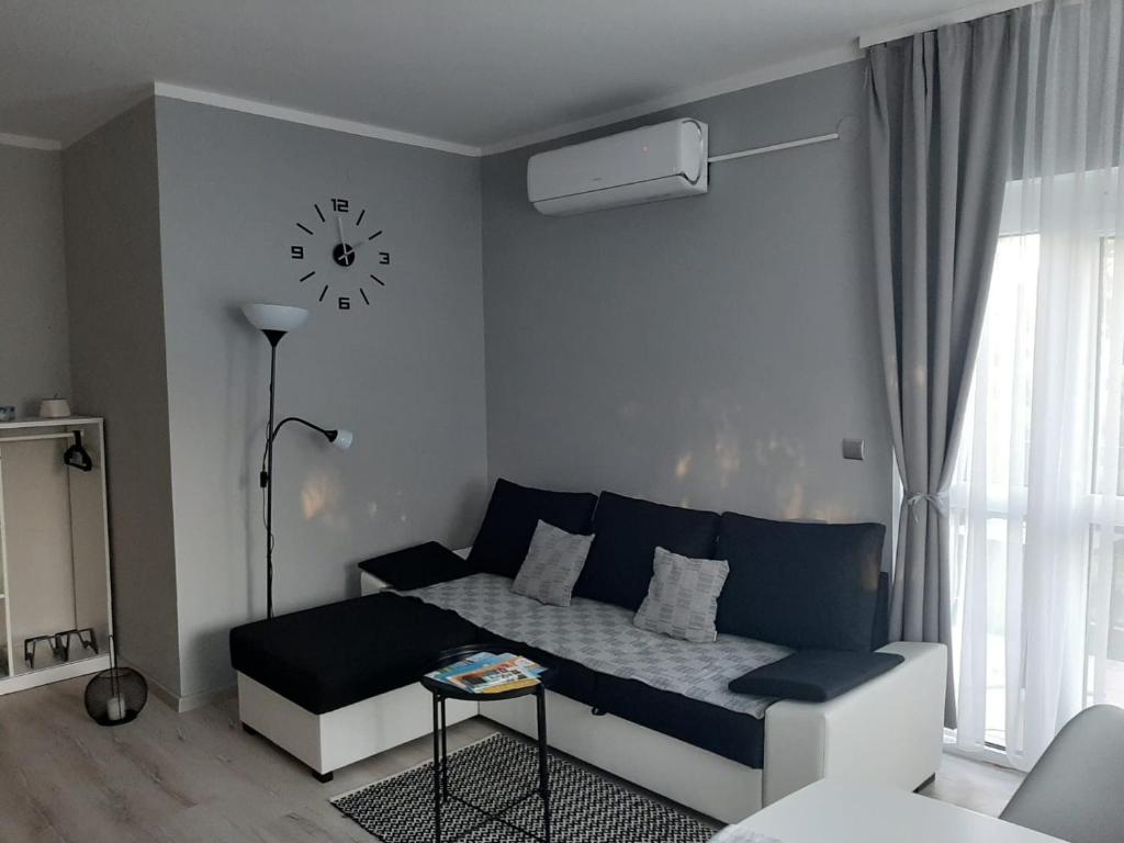 uma sala de estar com um sofá e um relógio na parede em Adam's Apartment em Kehidakustány