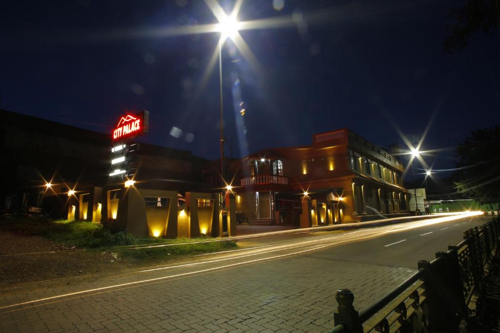 eine leere Straße in der Nacht mit Lichtern an einem Gebäude in der Unterkunft Hotel City Palace in Udagamandalam