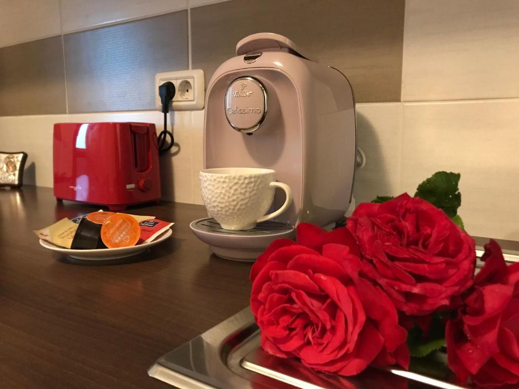 a kitchen counter with a coffee maker and red roses at Eli’s Apartament in Piatra Neamţ