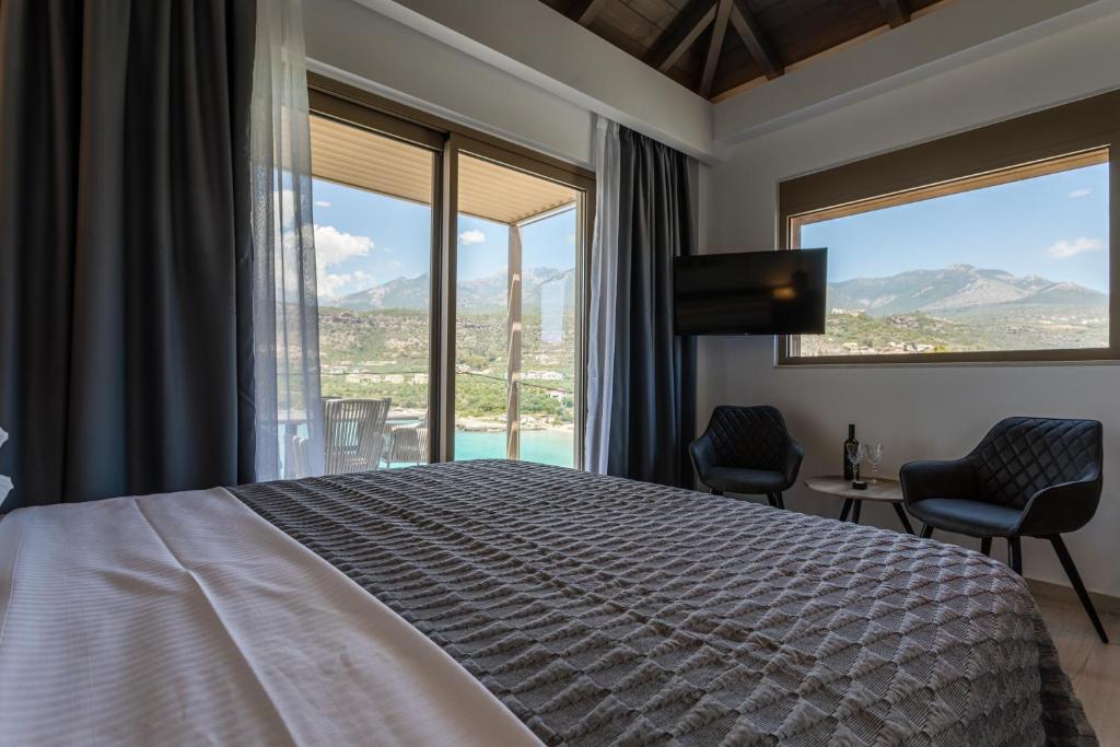 a bedroom with a bed and two chairs and windows at Lighthouse Apartments in Stoupa