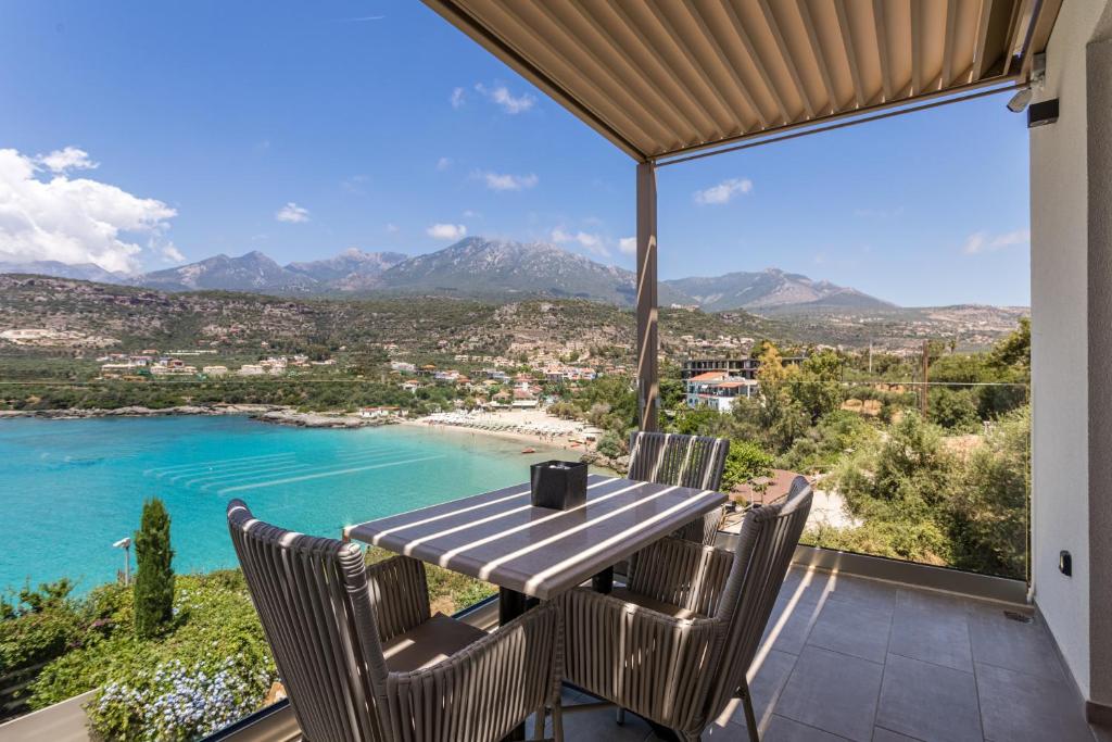 una mesa y sillas en un balcón con vistas al océano en Lighthouse Apartments, en Stoupa