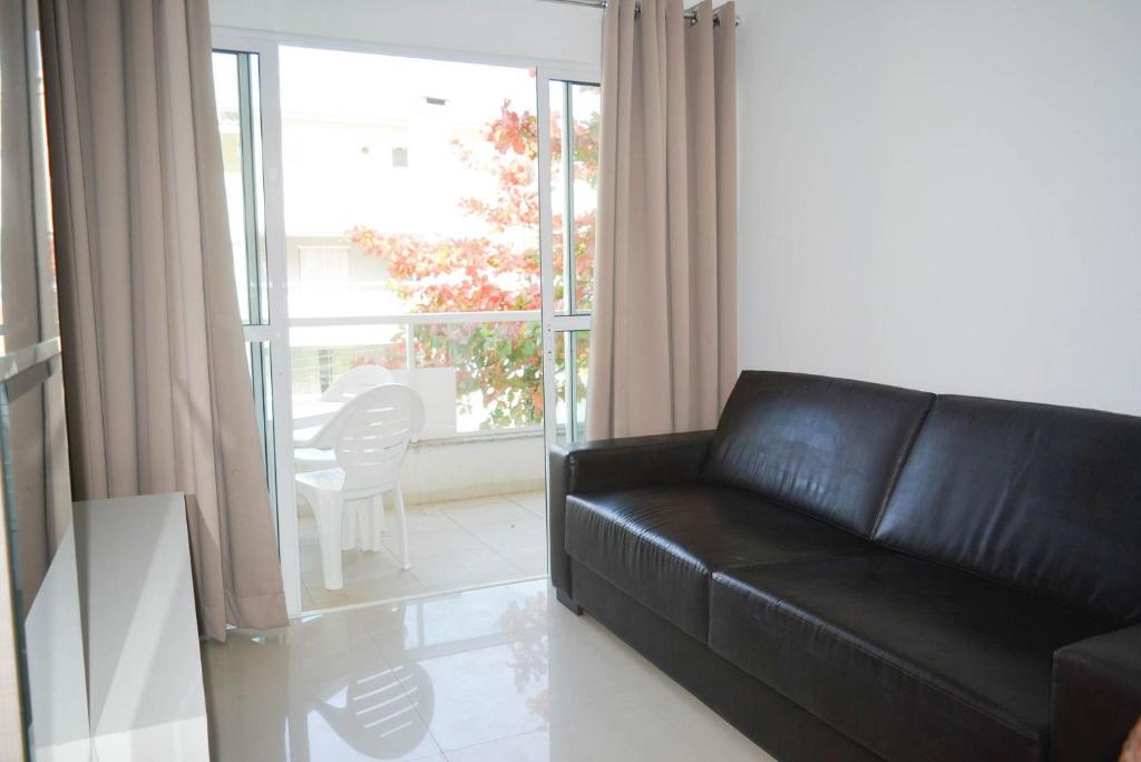 un sofá de cuero negro en una sala de estar con ventana en Residencial Amanda, en Bombinhas