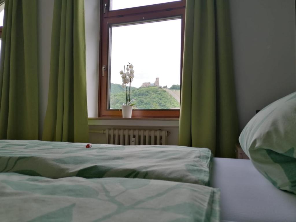 a bedroom with a bed and a window with green curtains at Mosel-Ferienwohnung Bewo in Bernkastel-Kues