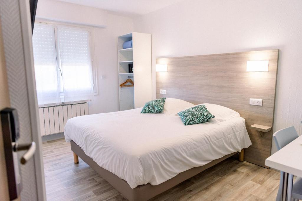 a bedroom with a large white bed with blue pillows at Hotel Atlantique in Mimizan-Plage