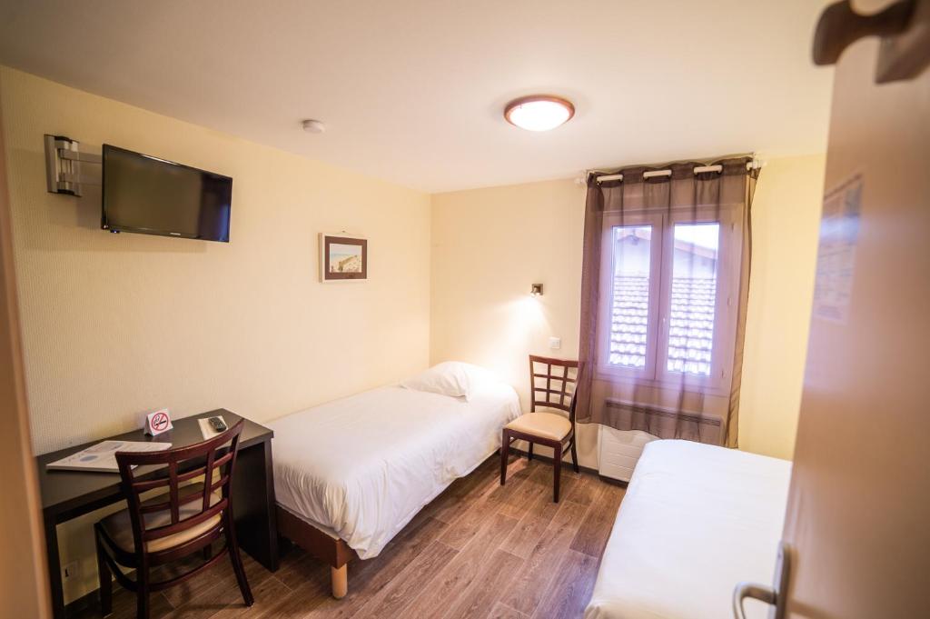 a hotel room with two beds and a desk and a window at Hotel Atlantique in Mimizan-Plage